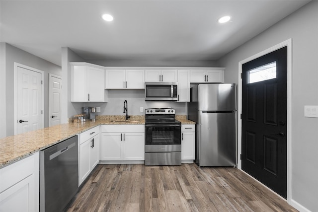 kitchen featuring dark wood-style flooring, stainless steel appliances, recessed lighting, white cabinetry, and a sink