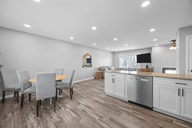 kitchen featuring light stone counters, light wood-style flooring, white cabinets, open floor plan, and stainless steel dishwasher