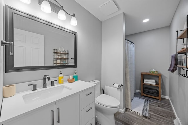 bathroom featuring toilet, baseboards, wood finished floors, and vanity