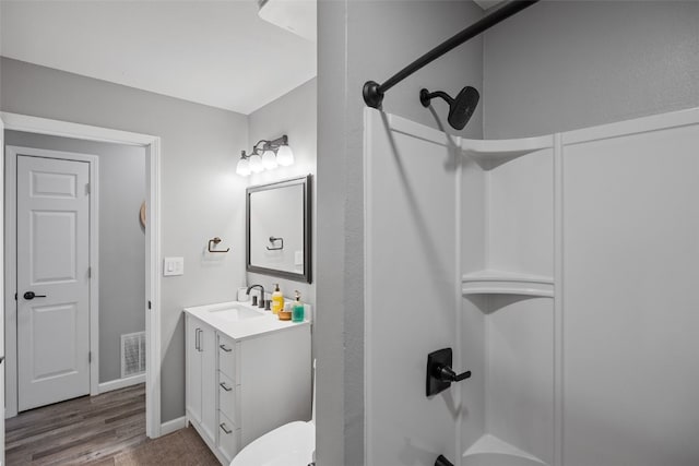 bathroom featuring wood finished floors, visible vents, vanity, and walk in shower