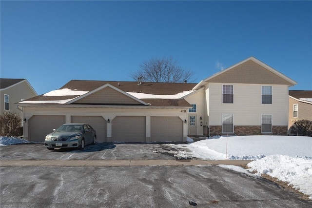 view of front of house featuring driveway, stone siding, and a garage