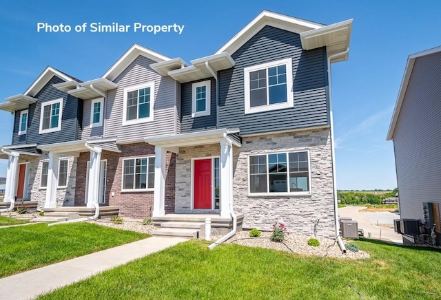 view of front of home with entry steps, stone siding, central AC, and a front lawn