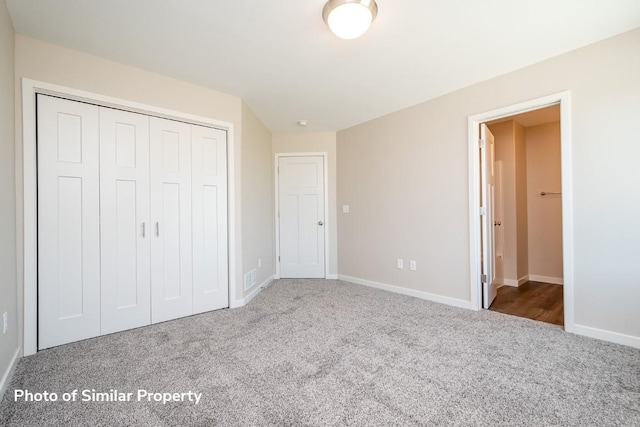 unfurnished bedroom with a closet, baseboards, and carpet flooring