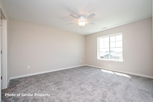 carpeted spare room with visible vents, a ceiling fan, and baseboards