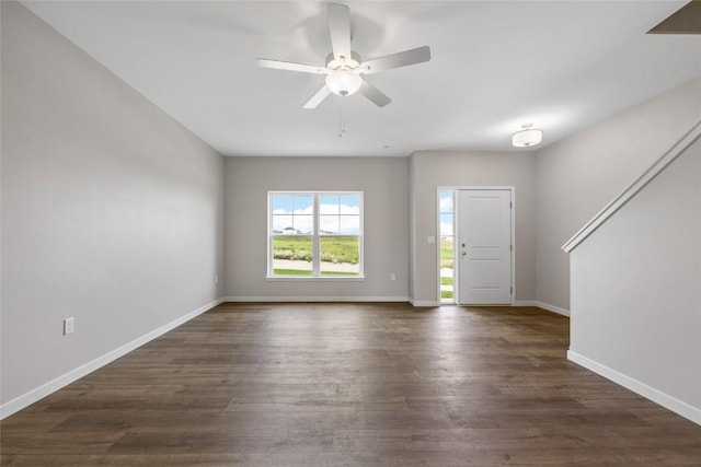 interior space with dark wood finished floors, a ceiling fan, and baseboards