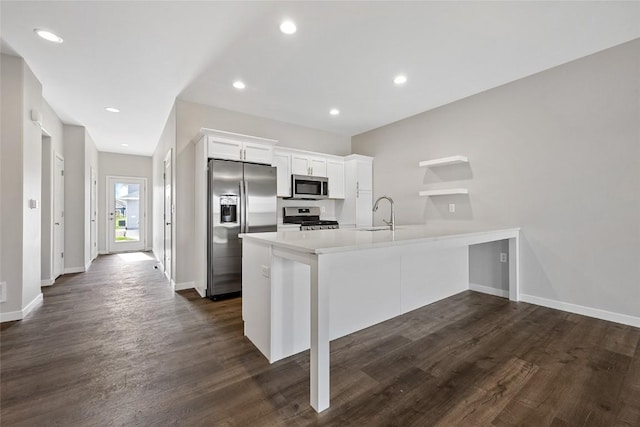 kitchen featuring a breakfast bar area, light countertops, appliances with stainless steel finishes, white cabinetry, and a peninsula