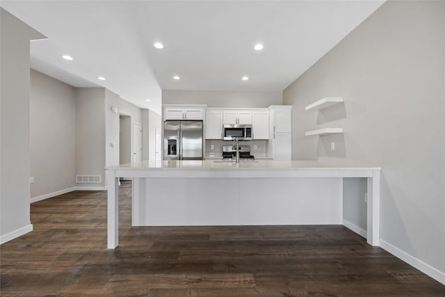 kitchen with visible vents, a breakfast bar area, stainless steel appliances, light countertops, and white cabinetry