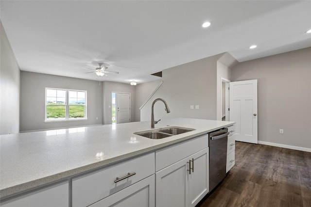 kitchen with light stone counters, a sink, white cabinets, stainless steel dishwasher, and dark wood-style floors