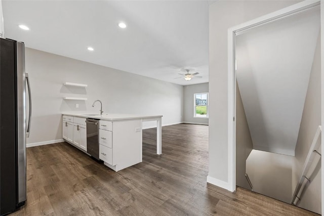 kitchen featuring open floor plan, stainless steel appliances, light countertops, a kitchen bar, and white cabinetry