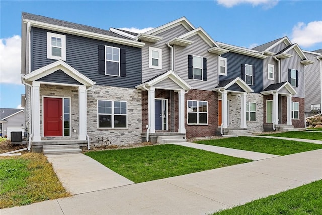 view of property featuring a front yard, stone siding, and entry steps