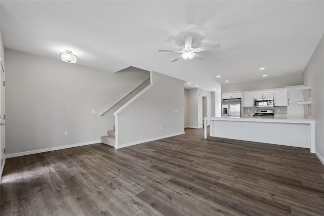 unfurnished living room with baseboards, stairway, and dark wood-type flooring