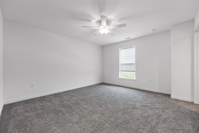 spare room with ceiling fan, baseboards, and dark colored carpet