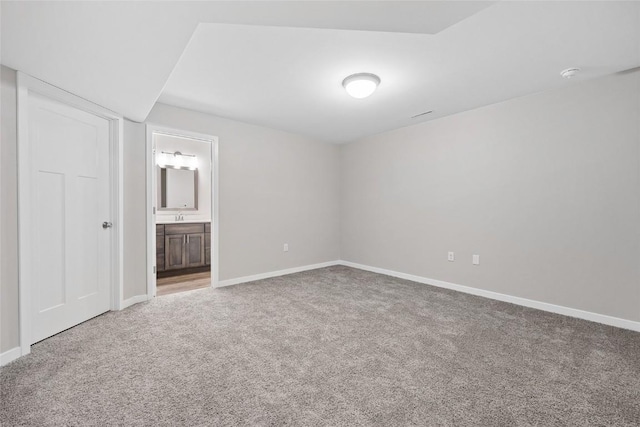 unfurnished bedroom featuring connected bathroom, baseboards, and carpet flooring