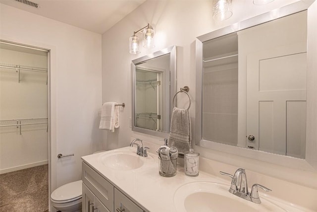 full bathroom with a walk in closet, visible vents, a sink, and double vanity