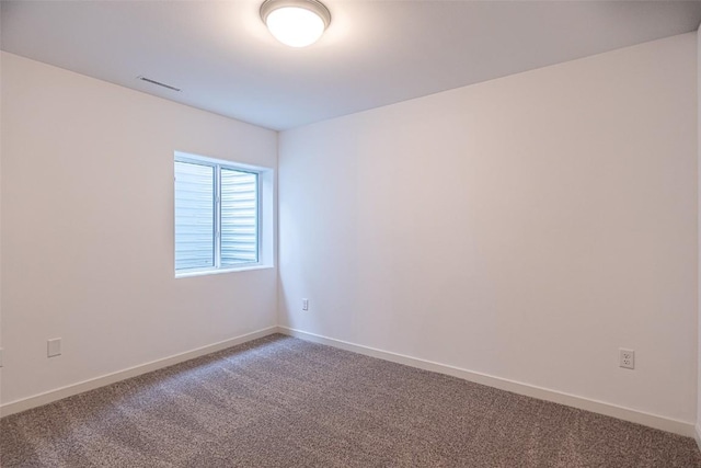 unfurnished room with carpet, visible vents, and baseboards