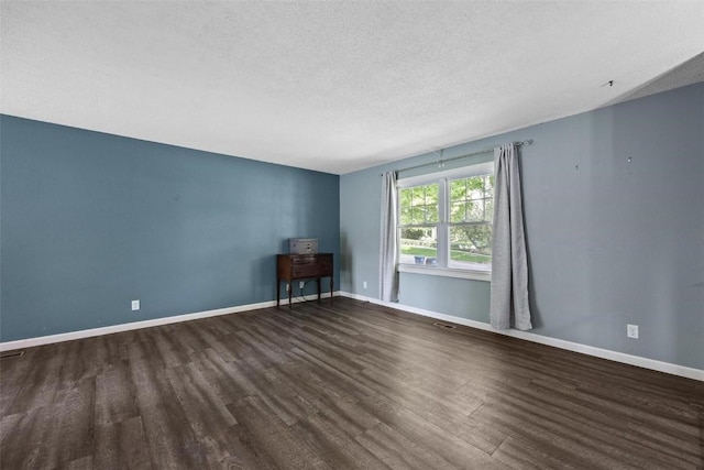 unfurnished room featuring dark wood-type flooring, a textured ceiling, and baseboards