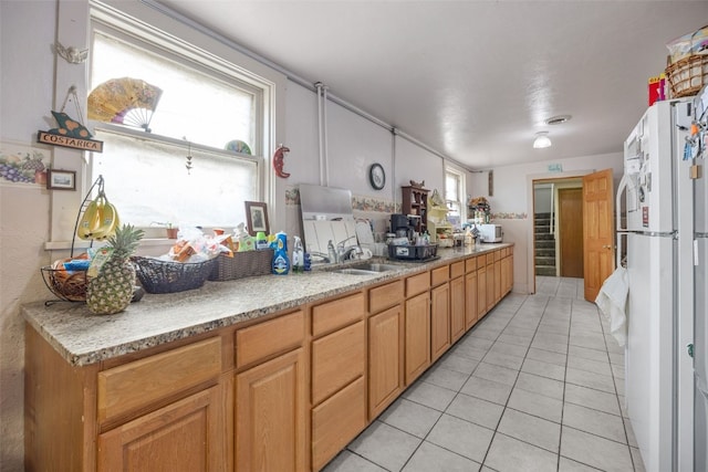 230 E Market St, Lisbon, IA 52253 - kitchen with plenty of natural light, freestanding refrigerator, a sink, and light tile patterned floors