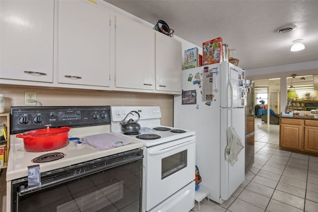 230 E Market St, Lisbon, IA 52253 - kitchen with light tile patterned floors, light countertops, visible vents, white cabinets, and white appliances