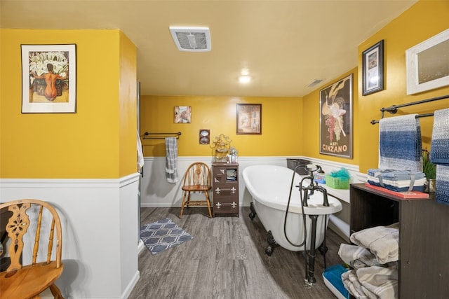 230 E Market St, Lisbon, IA 52253 - full bath featuring a wainscoted wall, a freestanding bath, wood finished floors, and visible vents