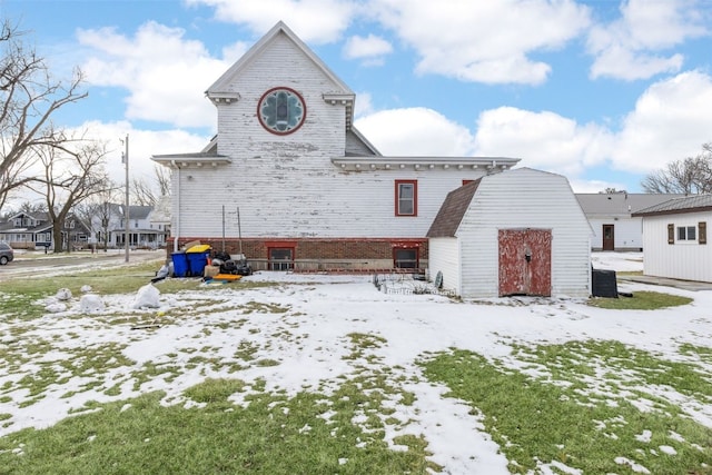 230 E Market St, Lisbon, IA 52253 - snow covered back of property featuring an outbuilding, brick siding, and central air condition unit