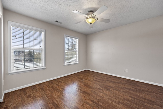 unfurnished room featuring visible vents, dark wood-type flooring, ceiling fan, a textured ceiling, and baseboards