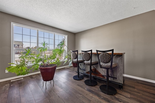 dining room featuring dark wood-type flooring, a textured ceiling, and baseboards