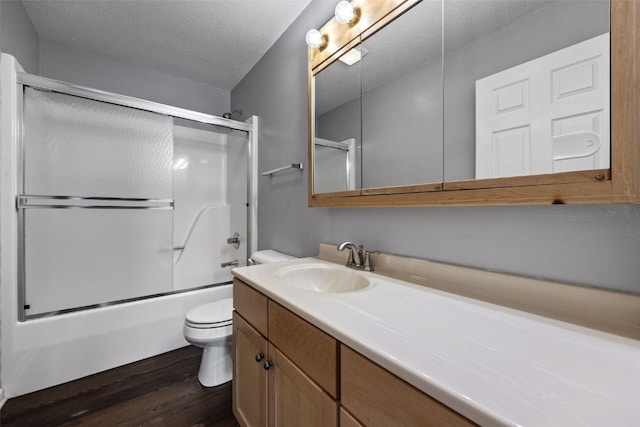 bathroom featuring shower / bath combination with glass door, toilet, a textured ceiling, vanity, and wood finished floors