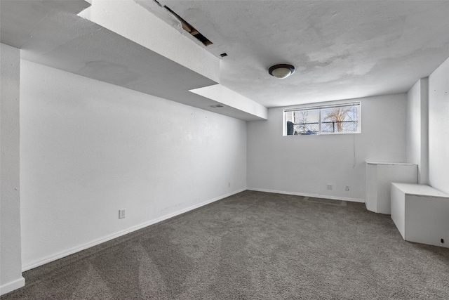 basement featuring baseboards and dark carpet