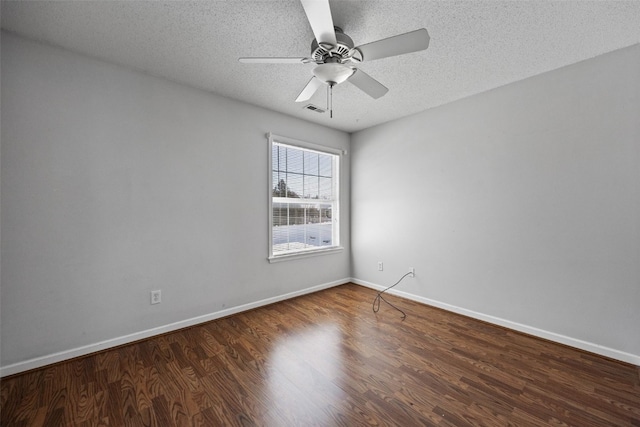 spare room featuring dark wood-style floors, visible vents, ceiling fan, a textured ceiling, and baseboards