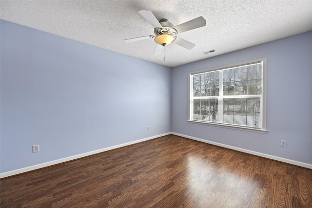 spare room with a textured ceiling, dark wood-type flooring, visible vents, and baseboards