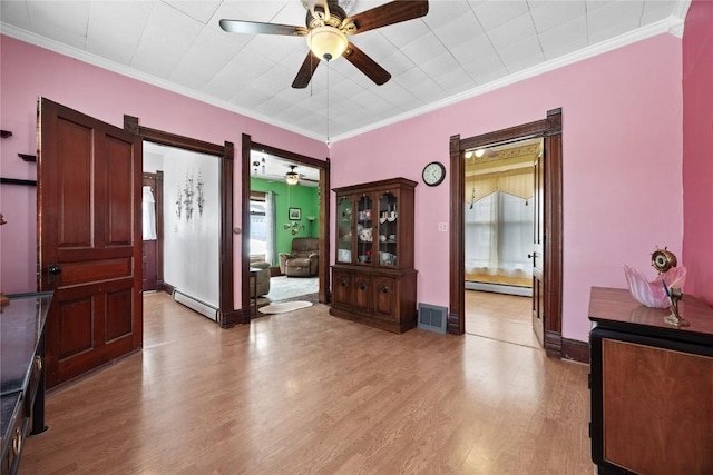 entryway with ornamental molding, a baseboard radiator, visible vents, and light wood-style flooring