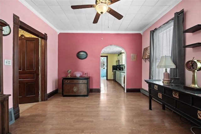 corridor with ornamental molding, arched walkways, and wood finished floors