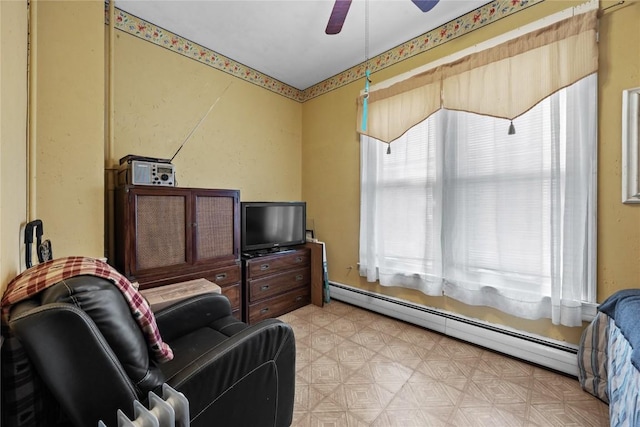 living area featuring light floors, baseboard heating, and a ceiling fan