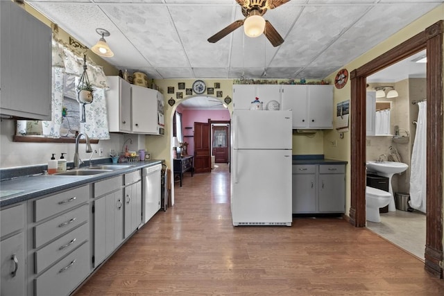 kitchen featuring arched walkways, dishwasher, dark countertops, freestanding refrigerator, and gray cabinets