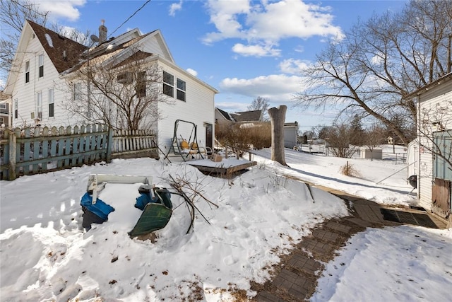 snow covered property featuring a garage and fence