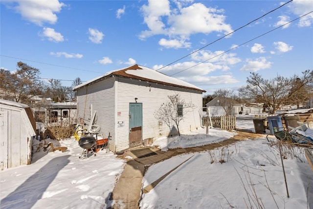 snow covered rear of property with fence