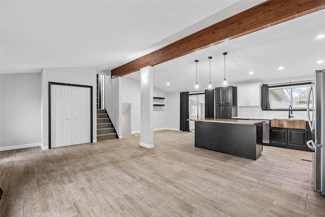 kitchen featuring light countertops, hanging light fixtures, open floor plan, a kitchen island, and a sink