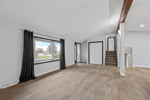 unfurnished living room featuring stairs, visible vents, lofted ceiling with beams, and light wood-style flooring