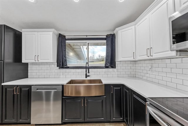 kitchen featuring light countertops, appliances with stainless steel finishes, a sink, and white cabinetry