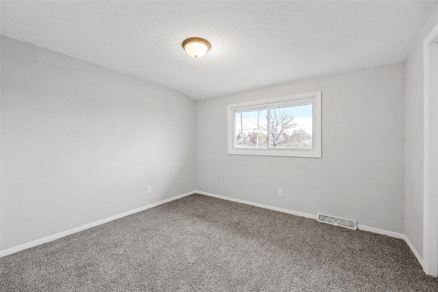 carpeted spare room featuring visible vents, a textured ceiling, and baseboards