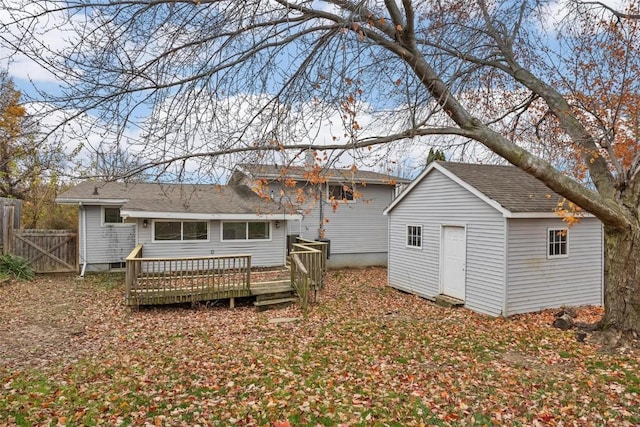 rear view of house with fence, an outdoor structure, and a wooden deck