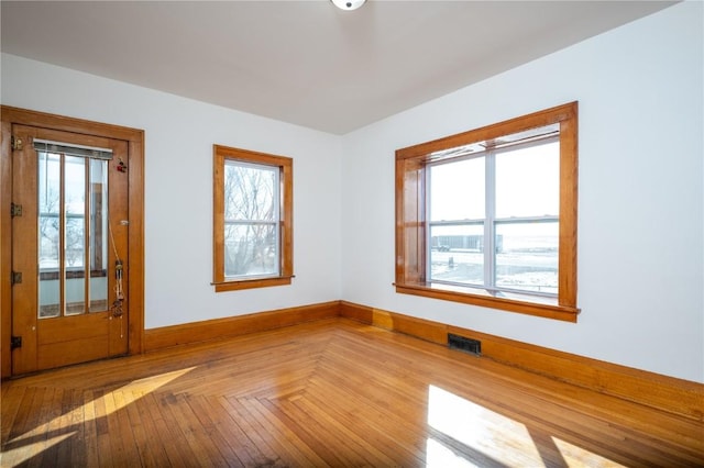 spare room with baseboards, visible vents, and a healthy amount of sunlight