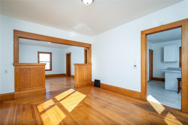 spare room with baseboards and light wood-style floors