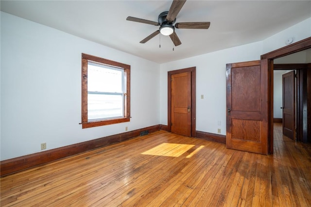 unfurnished bedroom featuring a ceiling fan, visible vents, baseboards, and wood finished floors