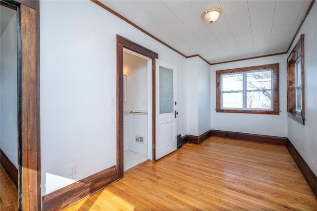 spare room featuring baseboards, light wood-type flooring, and crown molding