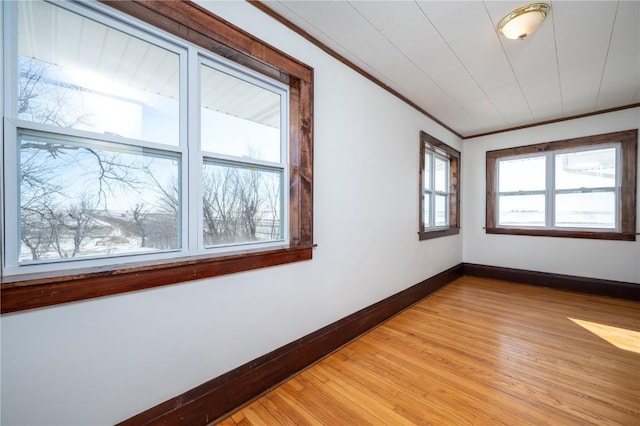 unfurnished room featuring baseboards, light wood-style floors, and crown molding