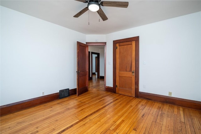 empty room featuring baseboards, a ceiling fan, visible vents, and light wood-style floors