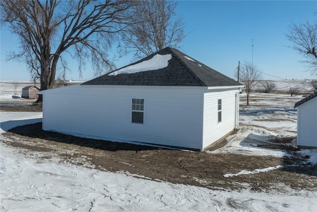 view of snowy exterior with roof with shingles