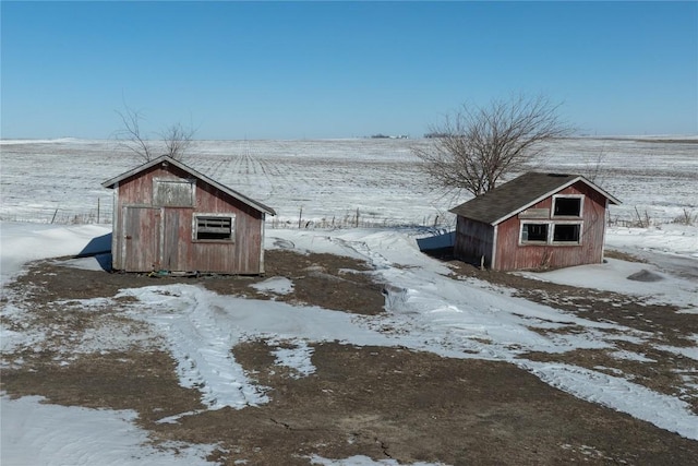 snowy yard with a storage shed, an outdoor structure, and a detached garage