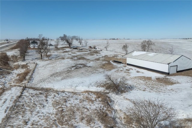 snowy yard featuring a detached garage and a rural view